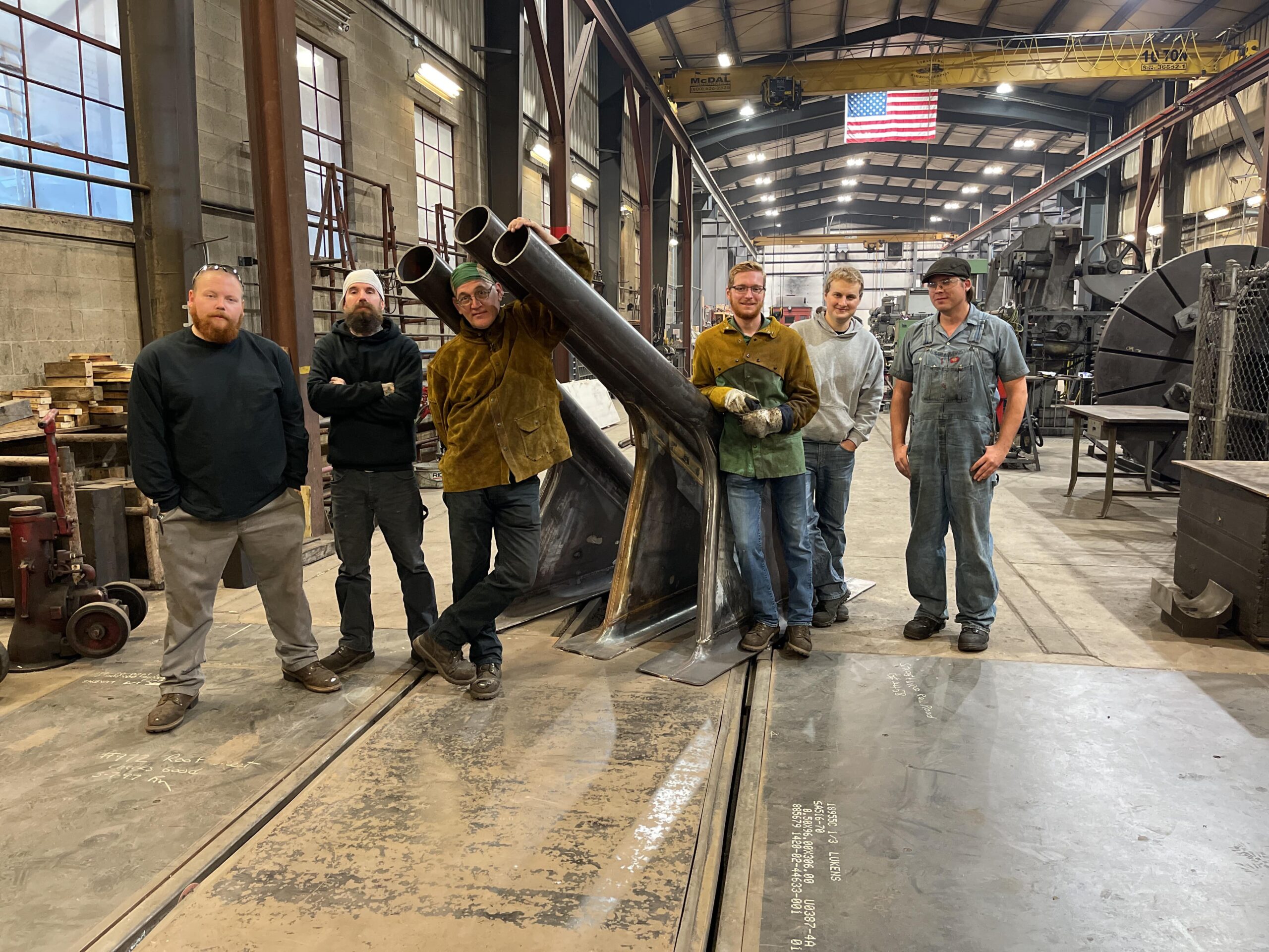 Strasburg Mechanical Employees standing by a steam engine part